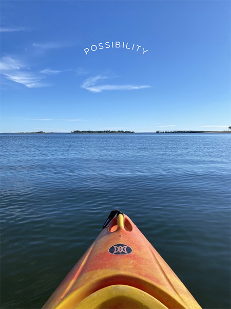 photo of tip of kayak in water looking at horizon, illustrating the word possibility overhead